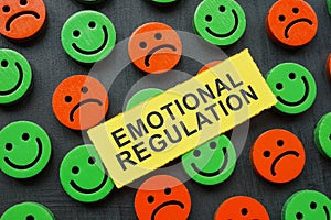 The inscription emotional regulation lies on happy and sad emoticons. photo
