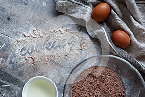 The inscription flour `Cooking` on a gray wooden messy background. Flour mixture, eggs and sunflower oil. Cozy culinary cover, con