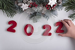 Inscription 2022 from gingerbread cookie, child hand taking cookie. New Year and Christmas decor