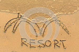 Inscription by hand RESORT in the beach sand in the surf line. Abstract.