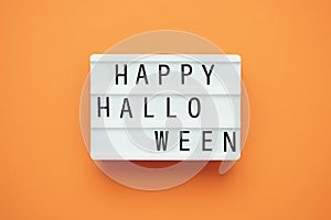 The inscription HAPPY HALLOWEEN on a lightbox on an orange background.