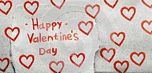 The inscription Happy Valentine`s Day in red pencil on piece of craft paper with many painted red hearts