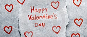 The inscription Happy Valentine`s Day in red pencil on piece of craft paper with many painted red hearts