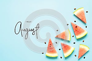 Inscription Hello August. Fresh red watermelon slice Isolated light blue background. Top view, Flat lay.