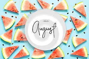 Inscription Hello August. Fresh red watermelon slice Isolated light blue background. Top view, Flat lay.