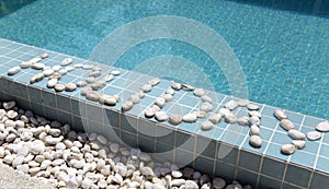 The inscription `holiday` is laid out by pebble on a pool side