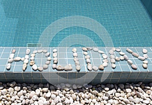 The inscription holiday is laid out by pebble on a pool side