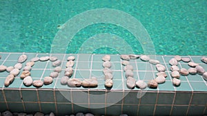 The inscription holiday is laid out by pebble on a pool side