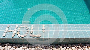 The inscription ` holiday ` is laid out by pebble on a pool side,stop-motion