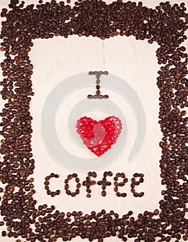 Inscription `I love coffee` made from coffee beans and red wicker rattan heart on wooden background