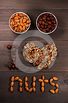Inscription I love nuts, from nuts, walnuts, almonds and hazelnuts and two white cups with nuts.