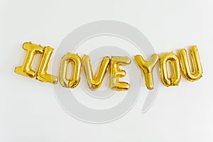 Inscription I LOVE YOU, foil inflatable gold ballon on the white background. Love, romance and Valentines day concept. Flat lay