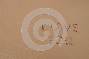 The inscription `I love you` painted on the sand.