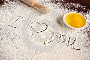 The inscription I love you on sprinkled flour, rolling pin and eggs. Baking recipes. Valentine`s day concept. Declaration of love