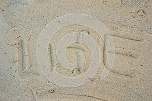 The inscription `life` on the sand