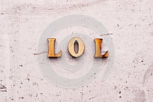 Inscription LOL LAUGHING OUT LOUD abbreviation in wooden letters on a light background