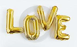 Inscription LOVE foil inflatable golden ballon on the white background. Love, romance and Valentines day concept. Flat lay