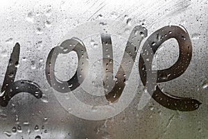 Inscription love on the wet glass rain