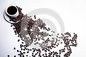 Inscription made of coffee beans on white background next to a cup of coffee