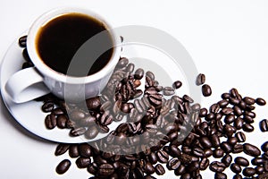 Inscription made of coffee beans on white background next to a cup of coffee