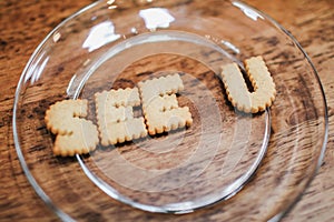 Inscription made of cookies `SEE YOU` Plate with alphabet Biscuits on wooden table