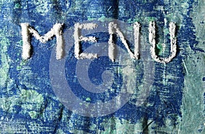 Inscription menu made of white salt  on blue grunge background
