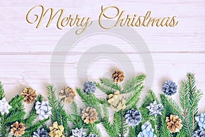 The inscription Merry Christmas on a light background. The composition of fir branches decorated with cones, gold and