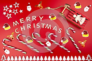 The Inscription Merry Christmas made of wooden letters, lying flat from above, isolated on a red background. Visible candy canes,