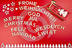 The Inscription Merry Christmas made of wooden letters, lying flat from above, isolated on a red background. Visible candy canes,