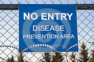 The inscription `NO ENTRY disease prevention area` on a blue plate