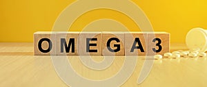 The inscription omega3 on wooden cubes, bright yellow background.