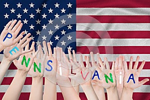 Inscription Pennsilvania on the children`s hands against the background of a waving flag of the USA