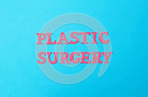 Inscription plastic surgery in red letters on a blue background. The concept of procedures in plastic surgeons photo