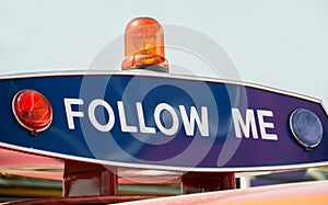 The inscription on the police car `Follow Me`, flashing lights red blue and orange flasher. The demand will stop, pursue.