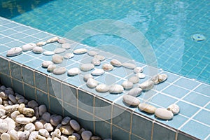 The inscription `pool` is laid out by pebble on a pool side