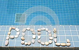 The inscription `pool` is laid out by pebble on a pool side