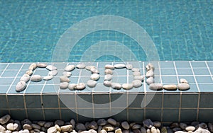 The inscription `pool` is laid out by pebble on a pool side