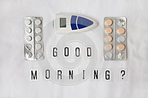 Inscription question Good morning, pills, thermometer on crumpled white sheet. Awakening concept with headache, fever, medicine,