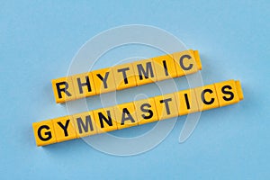The inscription rhytmic gymnastics written on yellow cubes against blue background.