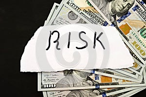 Inscription` risk` on white paper and dollars on a black background