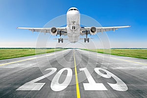 The inscription on the runway 2019 surface of the airport runway texture with take off airplane. Concept of travel in the new year