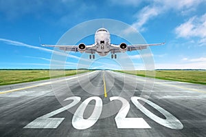 The inscription on the runway 2020 surface of the airport runway with take off aircraft. Concept of travel in the new year,