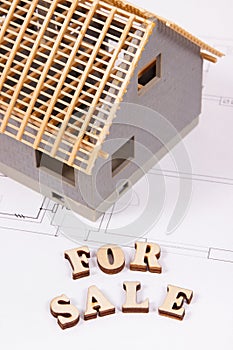 Inscription for sale and toy house under construction on electrical drawing, concept of selling and buying home or flat