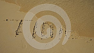 Inscription in the sand. A wave of water washes away the word time. Shortage concept. Slow motion