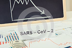 Inscription Sars-CoV-2, currencies dollar and declining chart as risk of financial crisis caused by virus