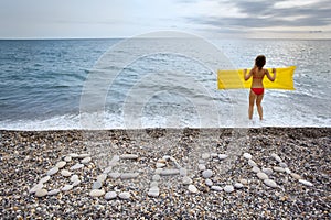 Inscription from stones BEACH at coast and woman