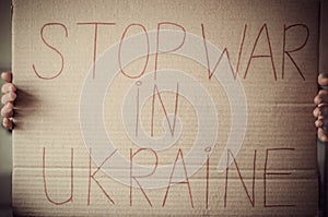 The inscription stop war in Ukraine on cardboard paper in female hands