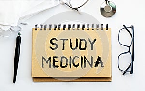 Inscription - STUDY MEDICINA. Written in a notepad to remind you of what\'s important. Top view of the table along with a photo