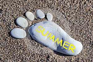 Inscription - summer, on a stone in the form of a footprint of a man made of stones in the sand