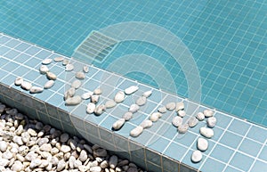 The inscription `swim` is laid out by pebble on a pool side